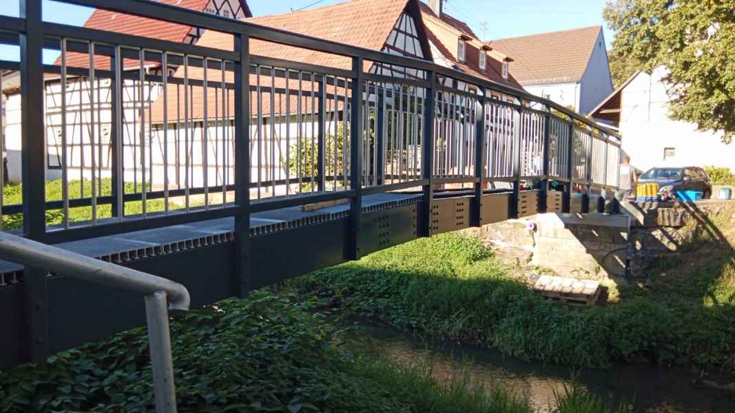 Geschwungene GFK-Brücke in Bad Hersfeld vor historischem Fachwerkhaus
